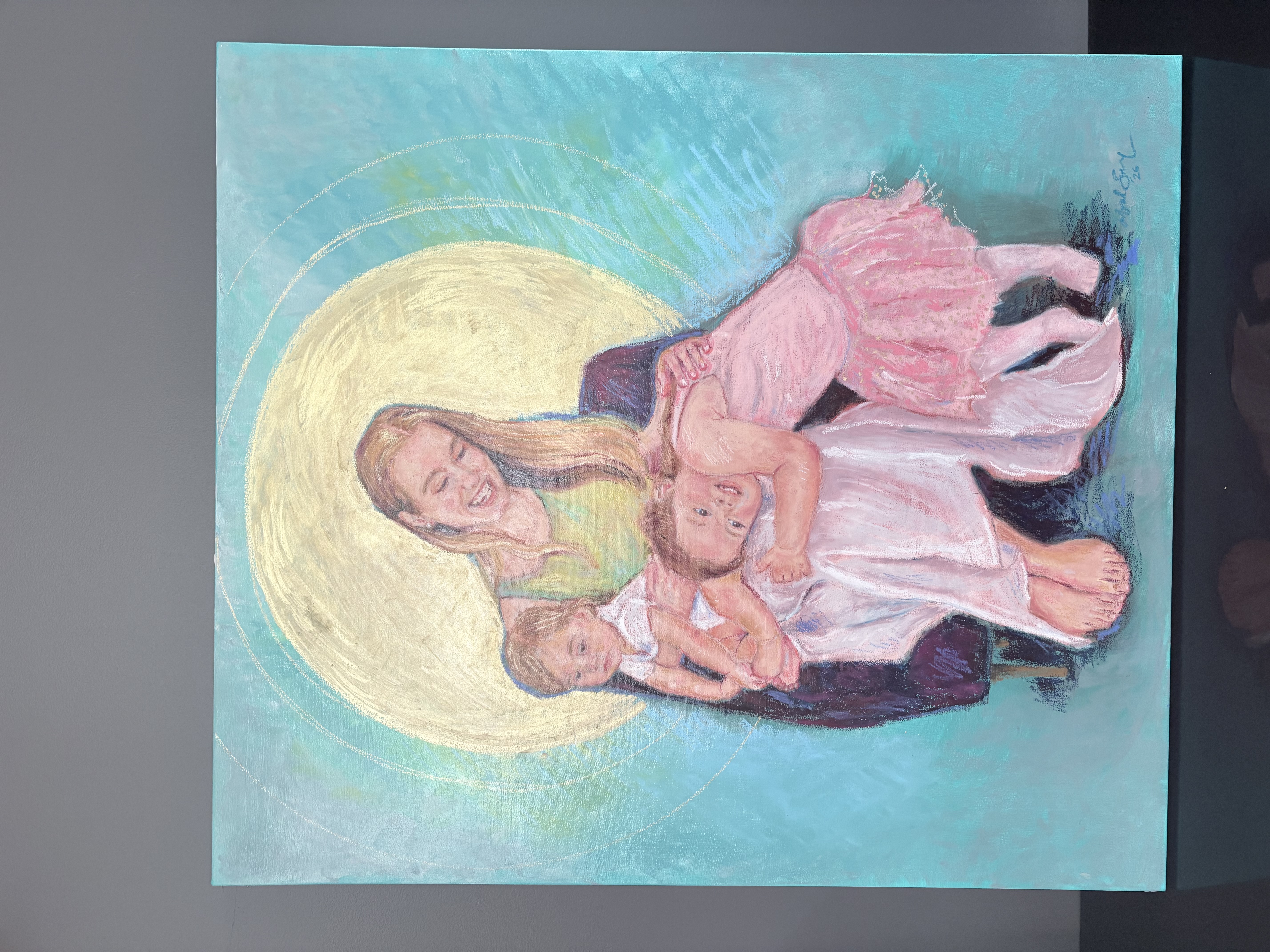 Family portrait — mother with two young children, teal background with golden halo